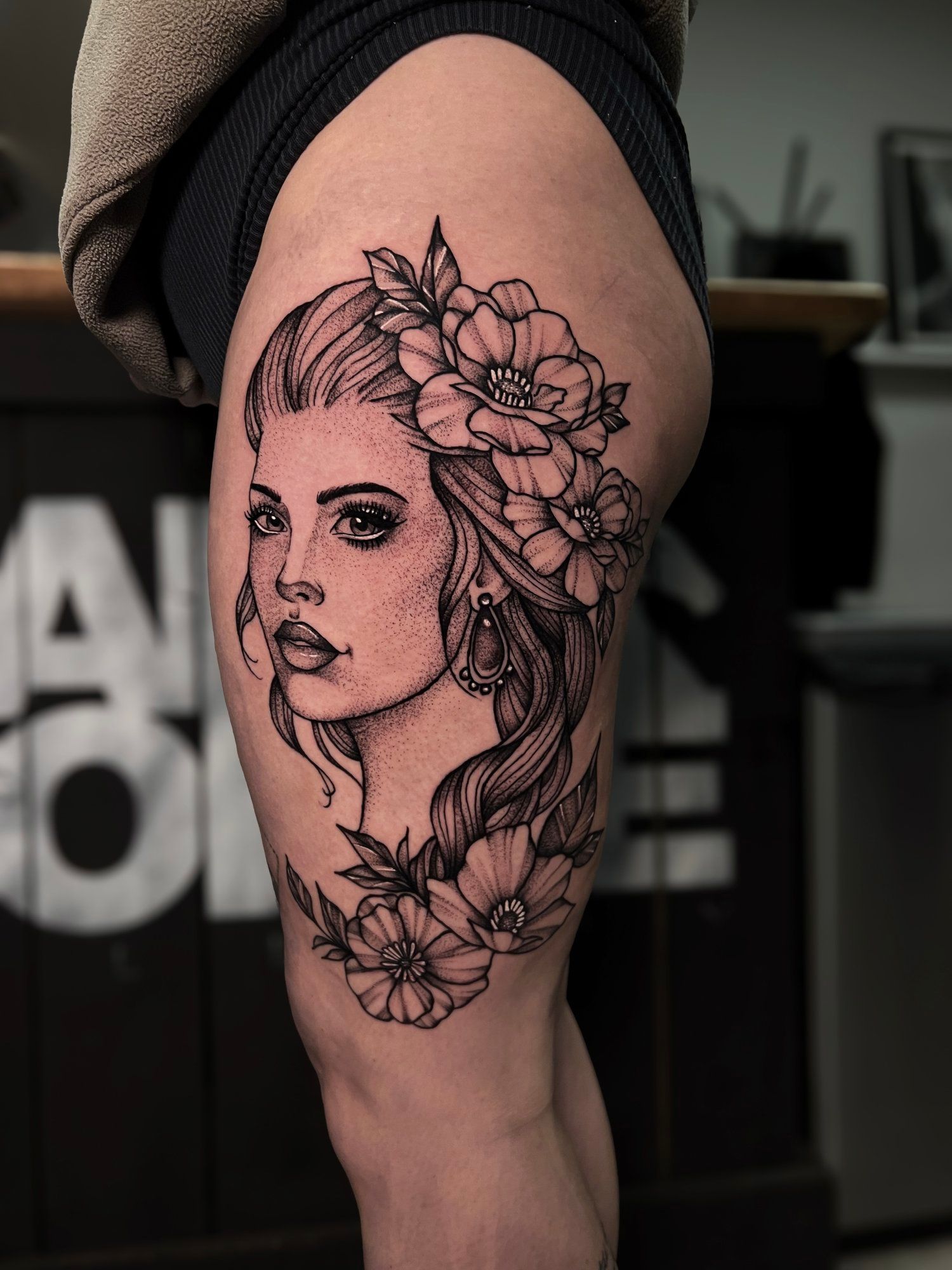 A woman has a tattoo of a woman 's face with flowers on her head.