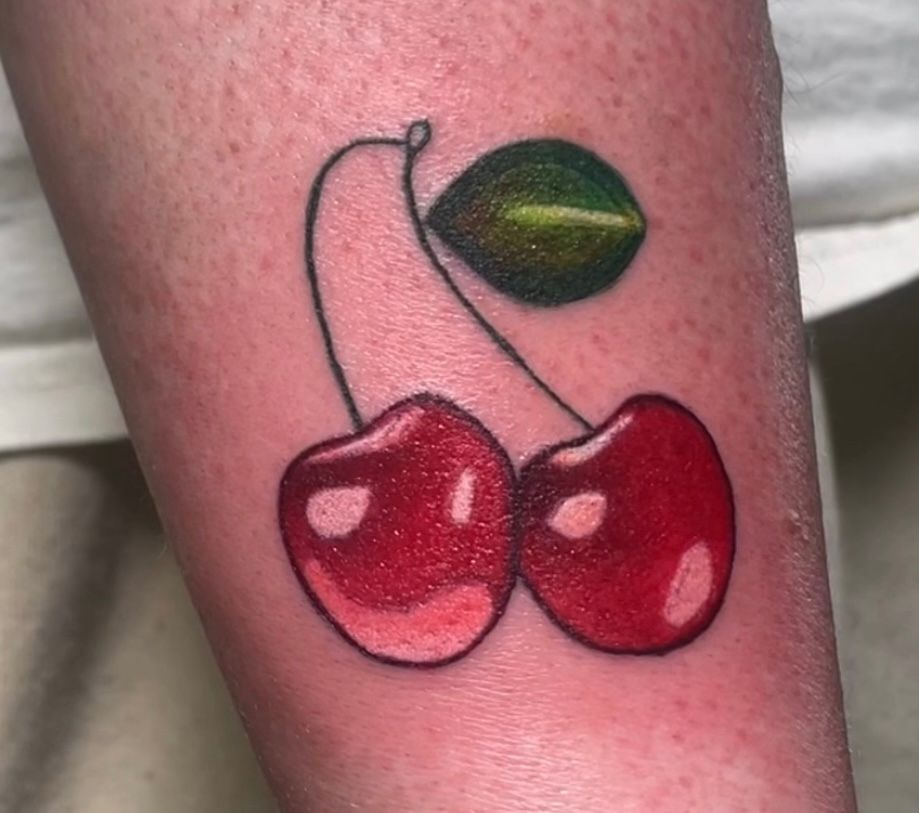 A person has a tattoo of two cherries on their forearm.