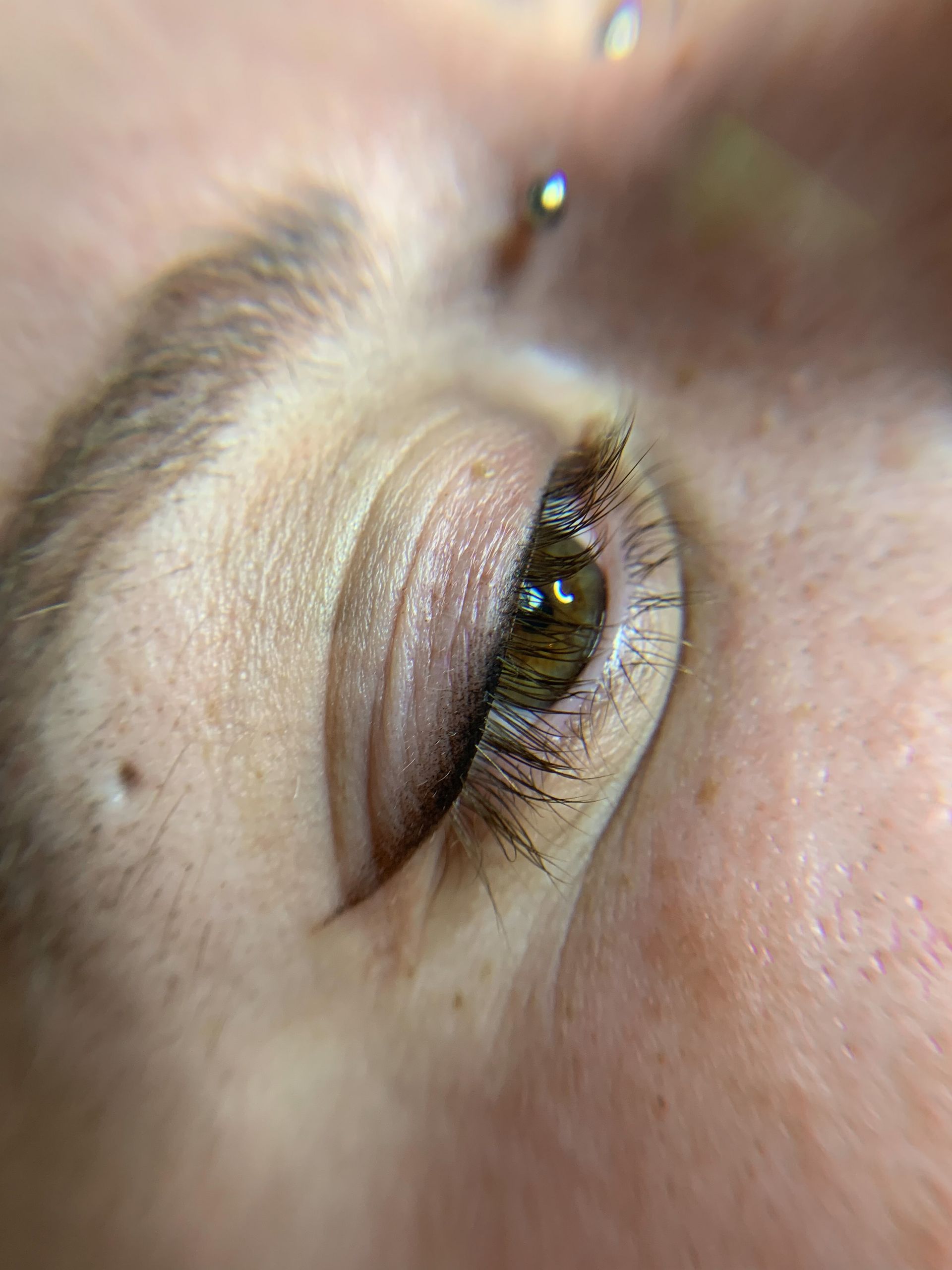 A close up of a woman 's eye with a nose ring.