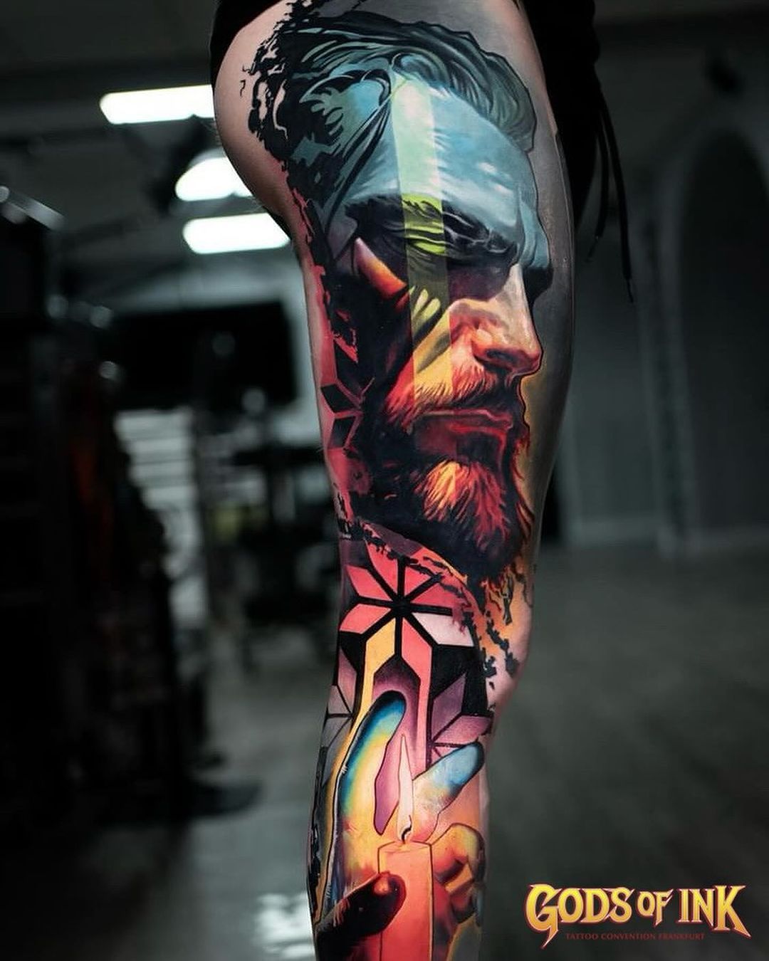 A woman has a tattoo of a bearded man on her leg.