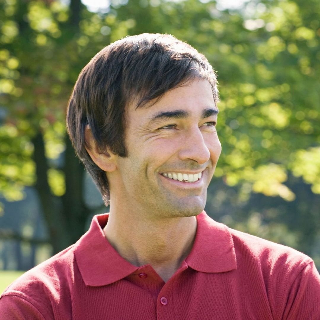 A man wearing a red polo shirt is smiling