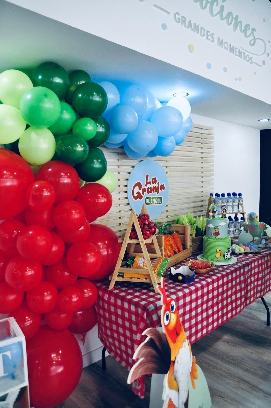 Mesa de aperitivos a cuadros con bebidas, frutas y una decoración de flamencos en un ambiente festivo.