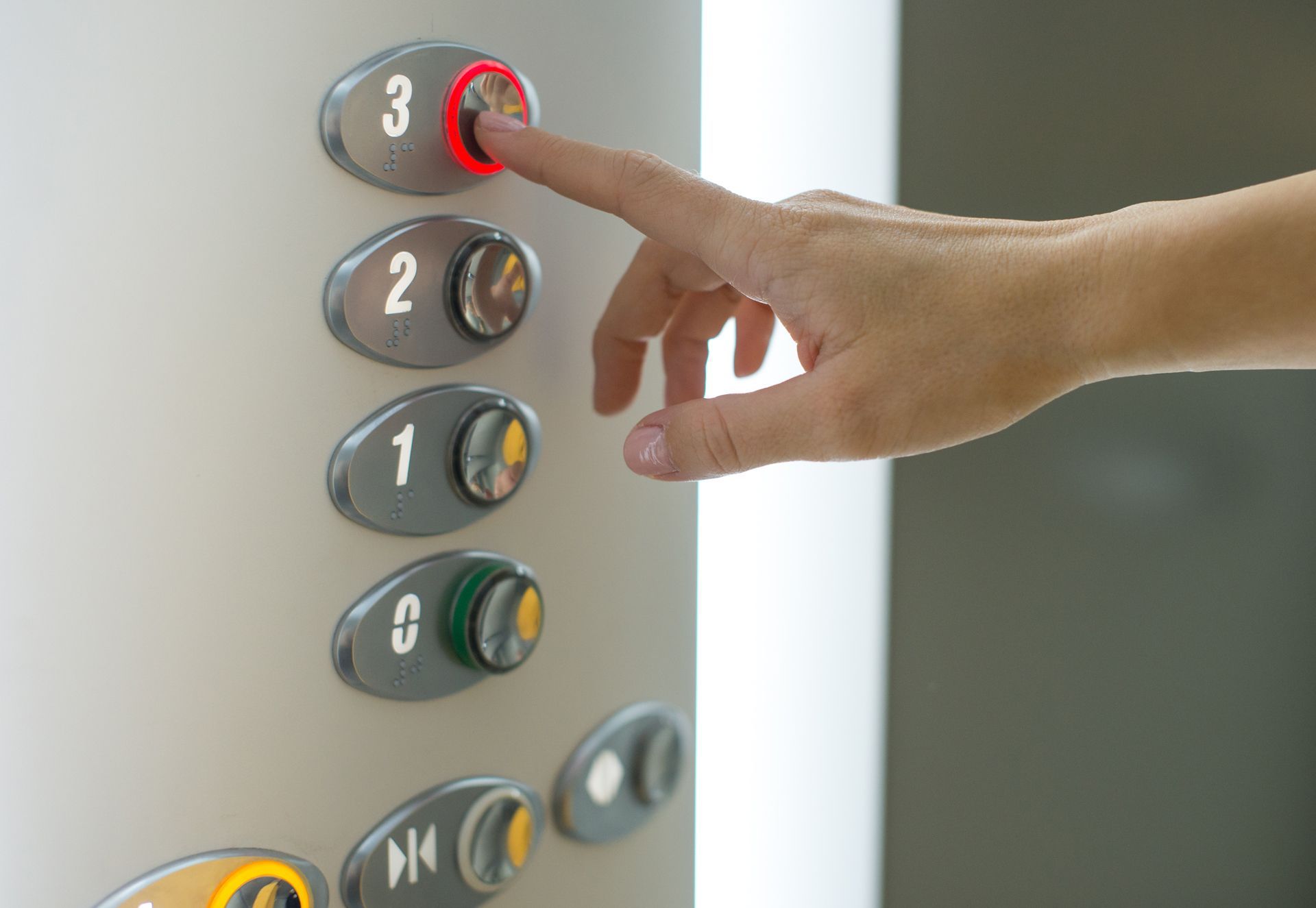 A person is pressing a red button on an elevator