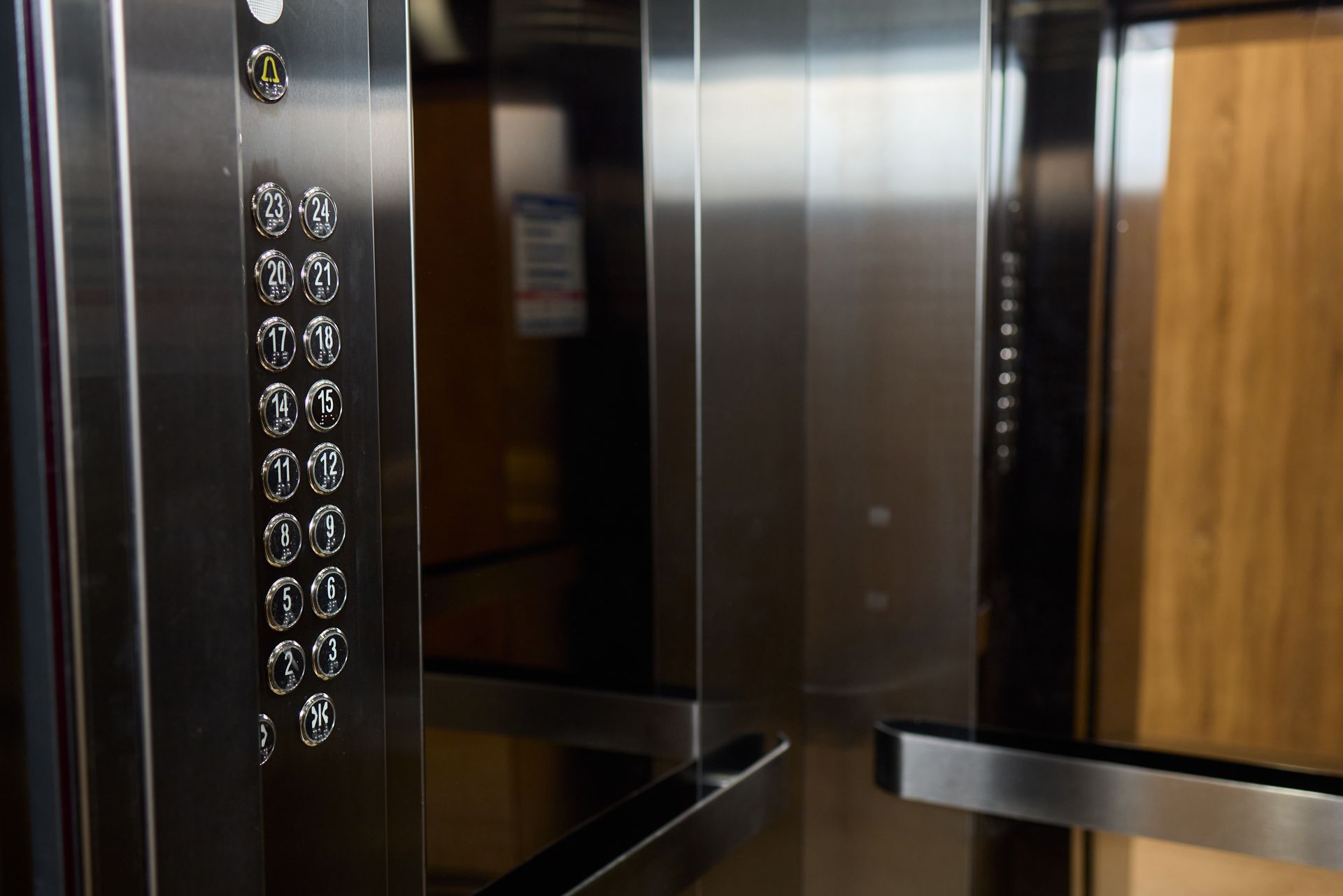 A close up of a stainless steel elevator with buttons and a wooden door