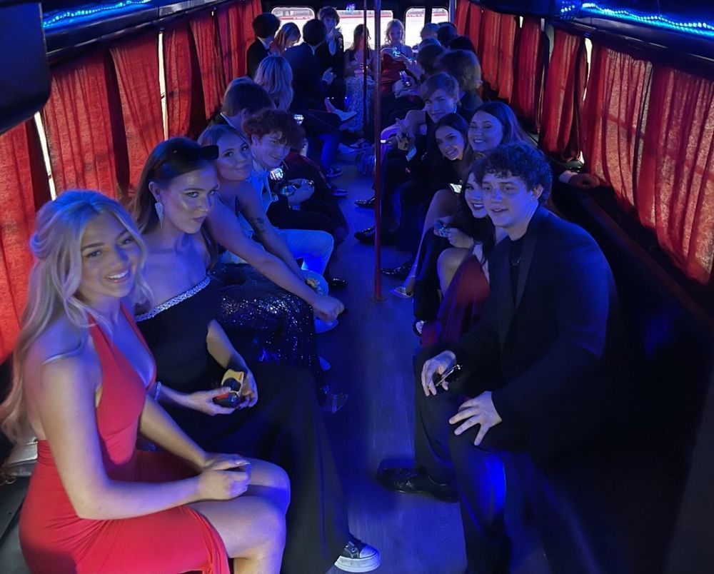 A group of people are sitting on a bus enjoying prom night party bus services.
