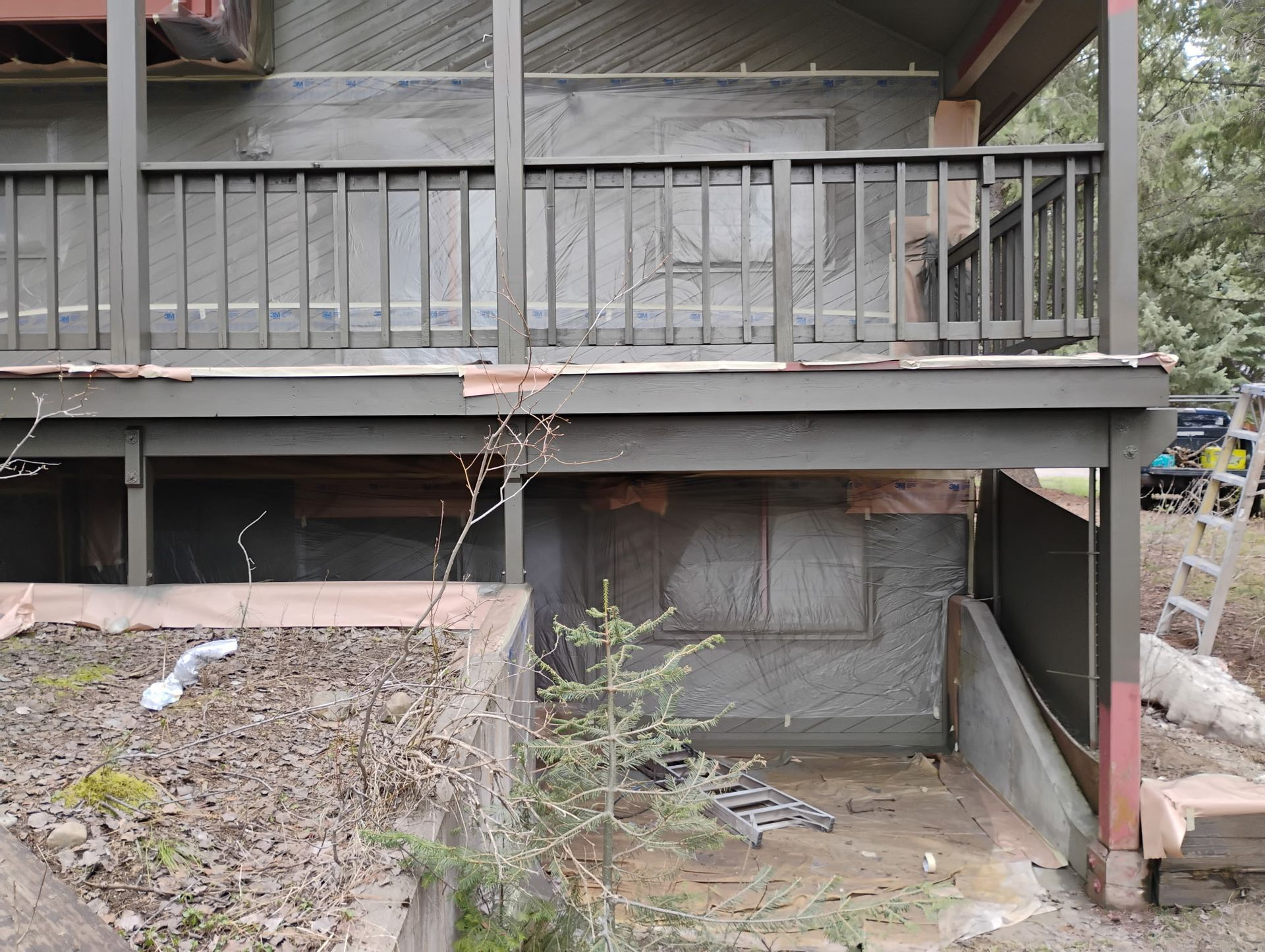 Under-house area with a small basement opening beneath a weathered wooden deck and porch.