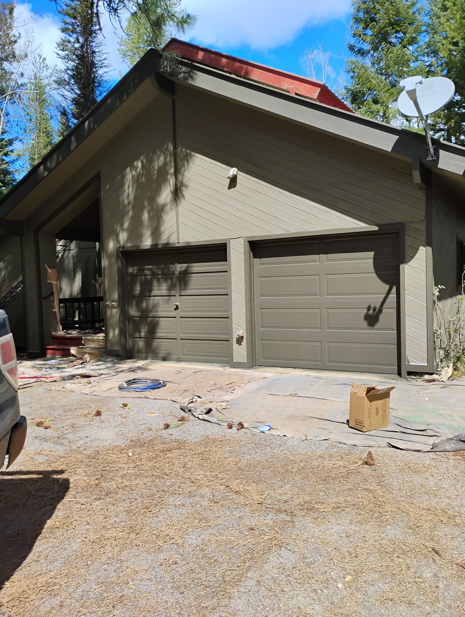 House with two-car garage and red roof, viewed from driveway under sunny sky