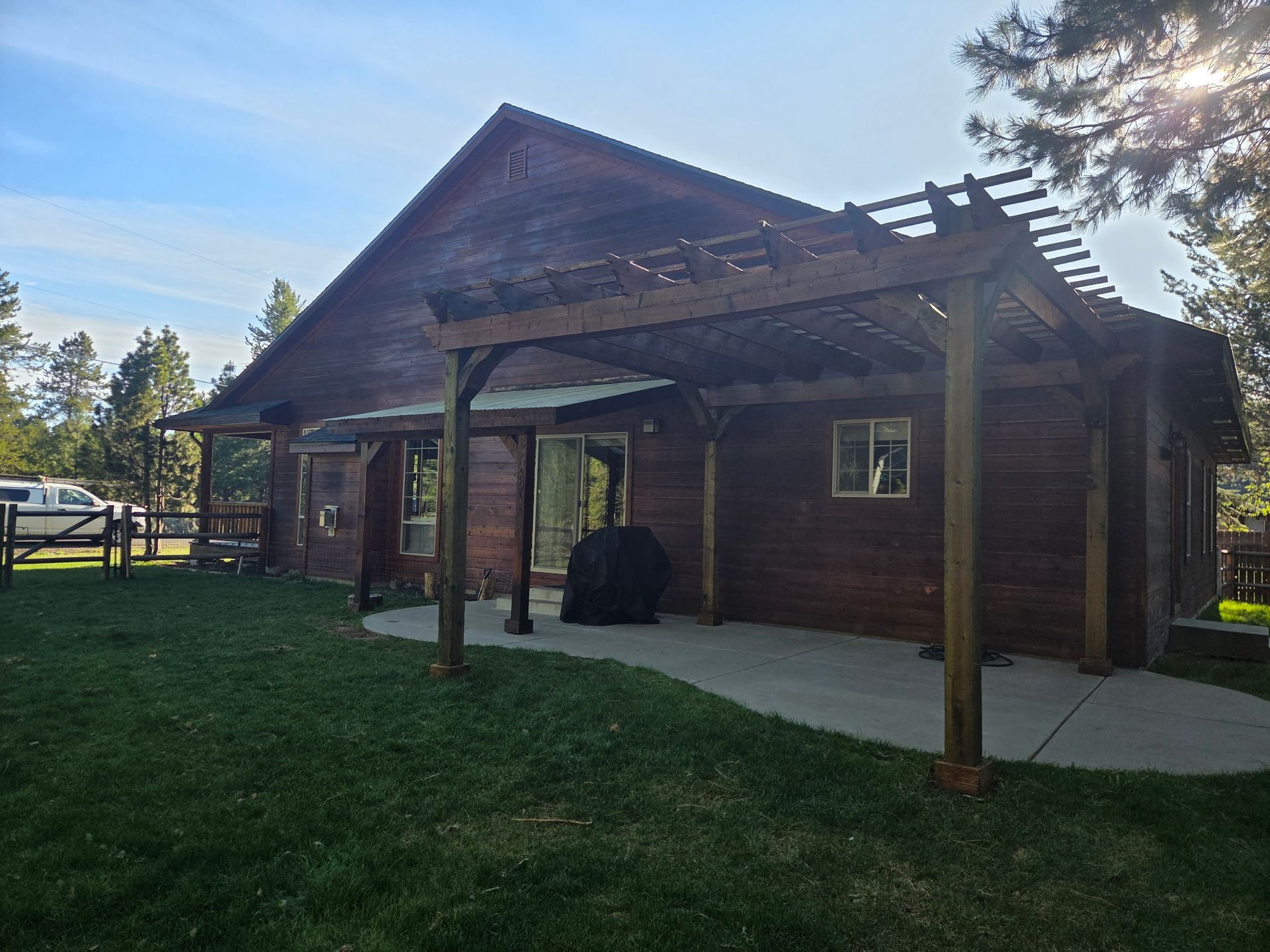 Rustic wooden cabin with covered porch and grassy yard in bright daylight