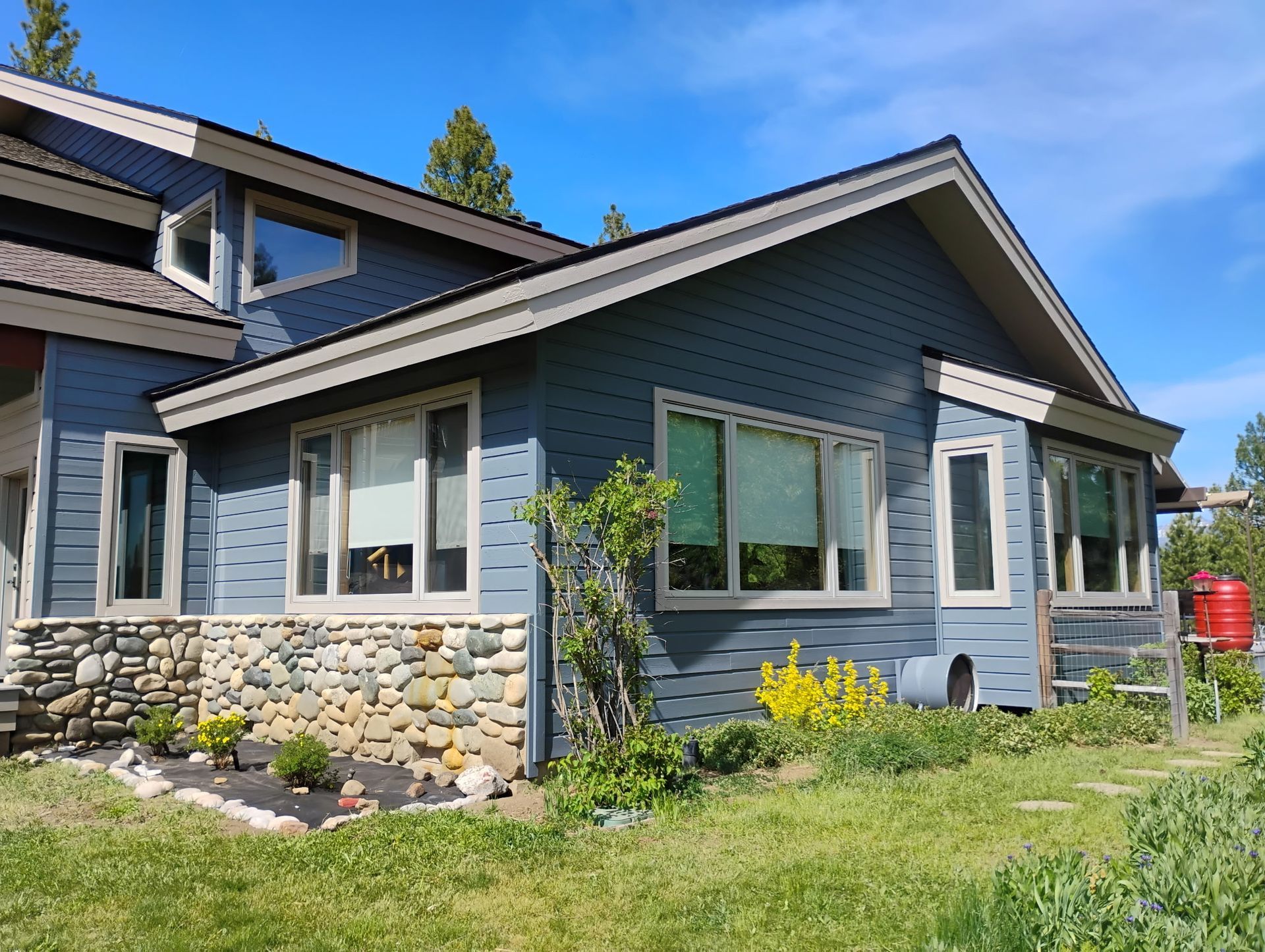 Blue house with stone foundation and white-trimmed windows in a grassy yard
