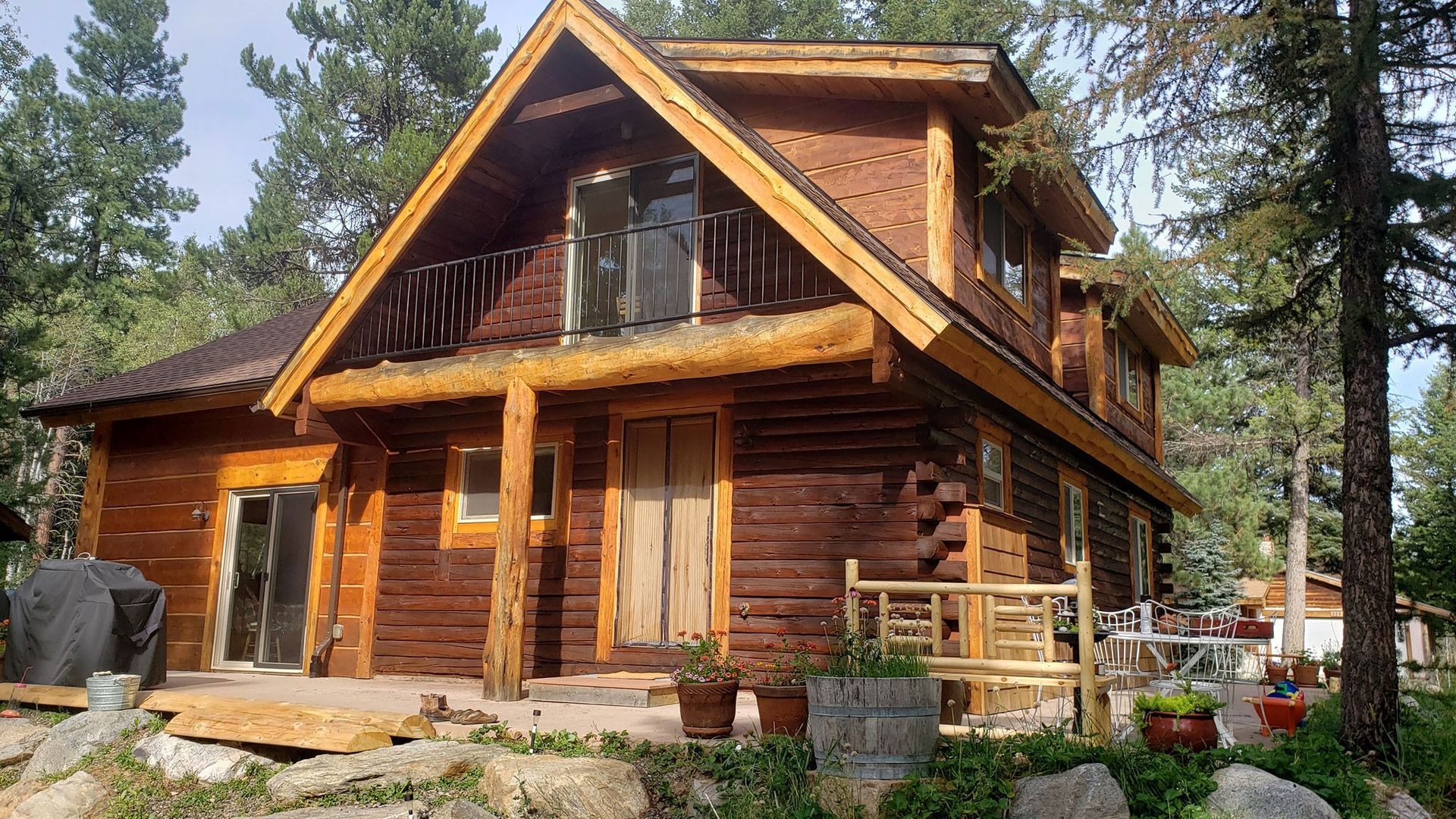 A large log cabin is surrounded by trees and rocks.