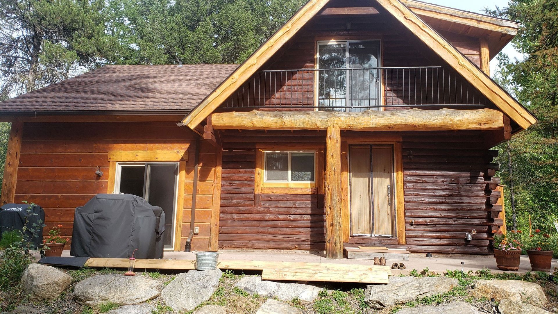 A log cabin with a balcony and a grill on the porch