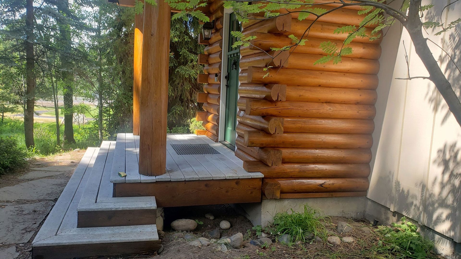 A log cabin with a porch and stairs in front of it