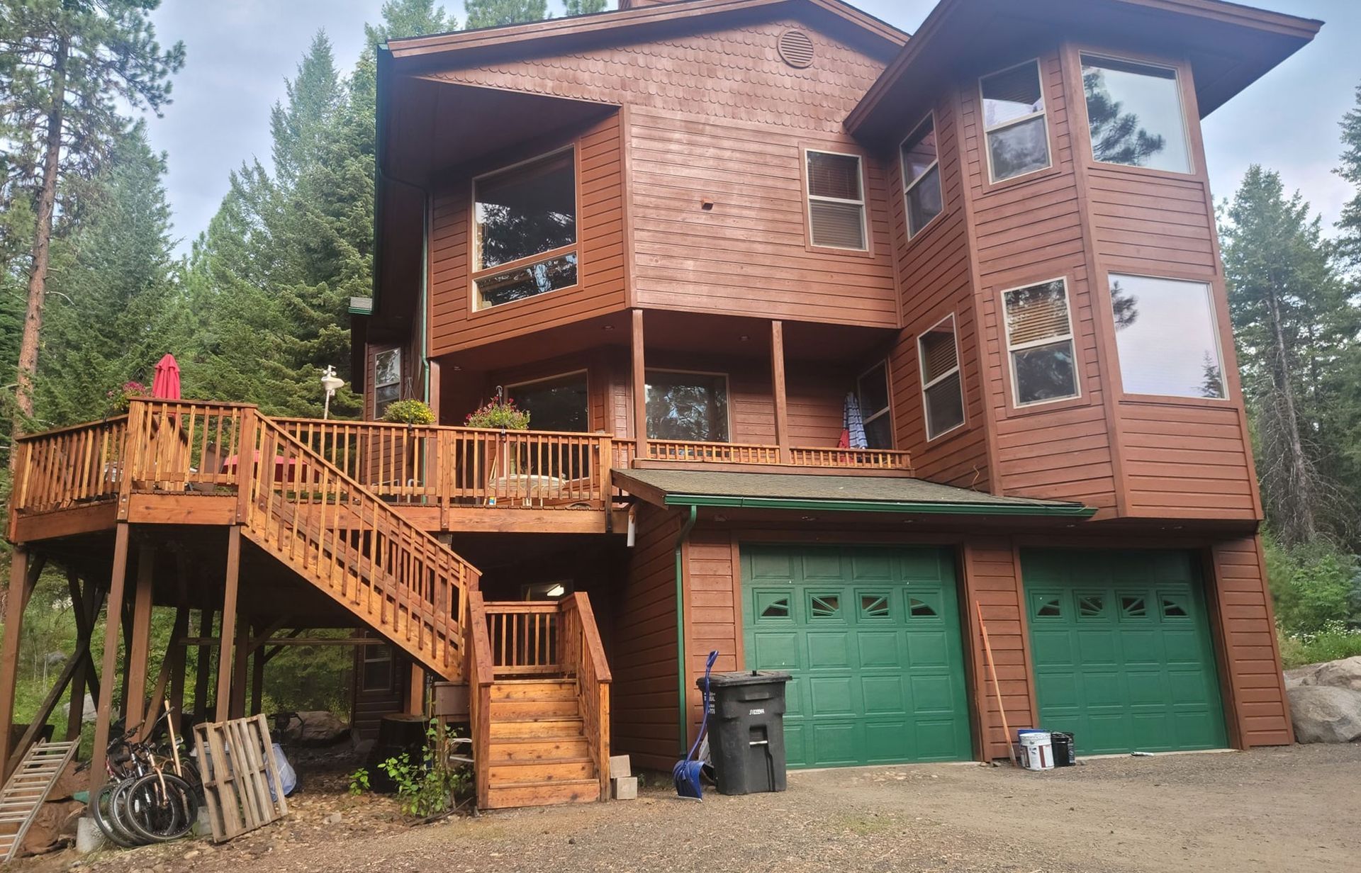A large wooden house with a green garage and stairs