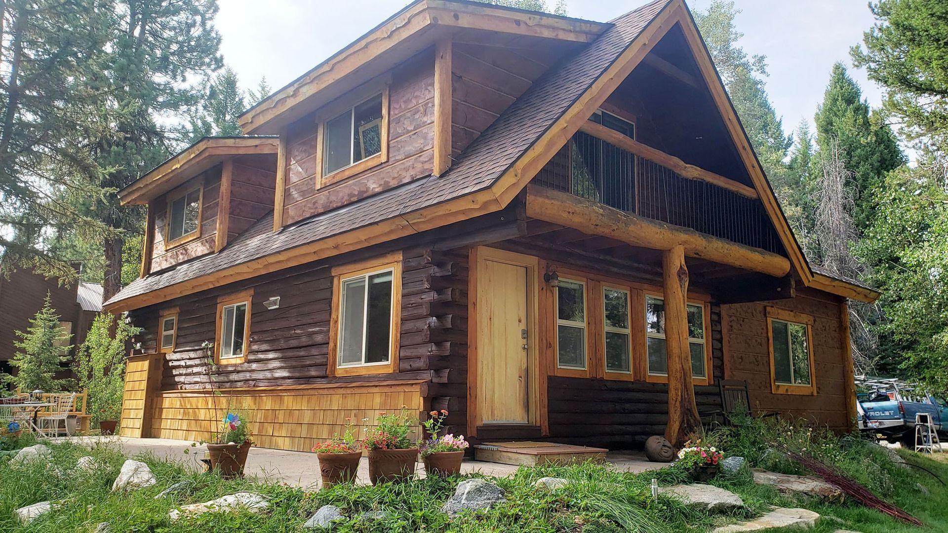 A large log cabin is sitting in the middle of a lush green forest.