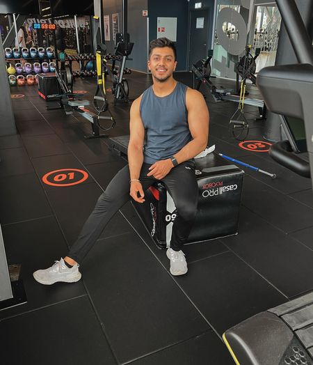 Kamal is sitting on a bench in a gym.