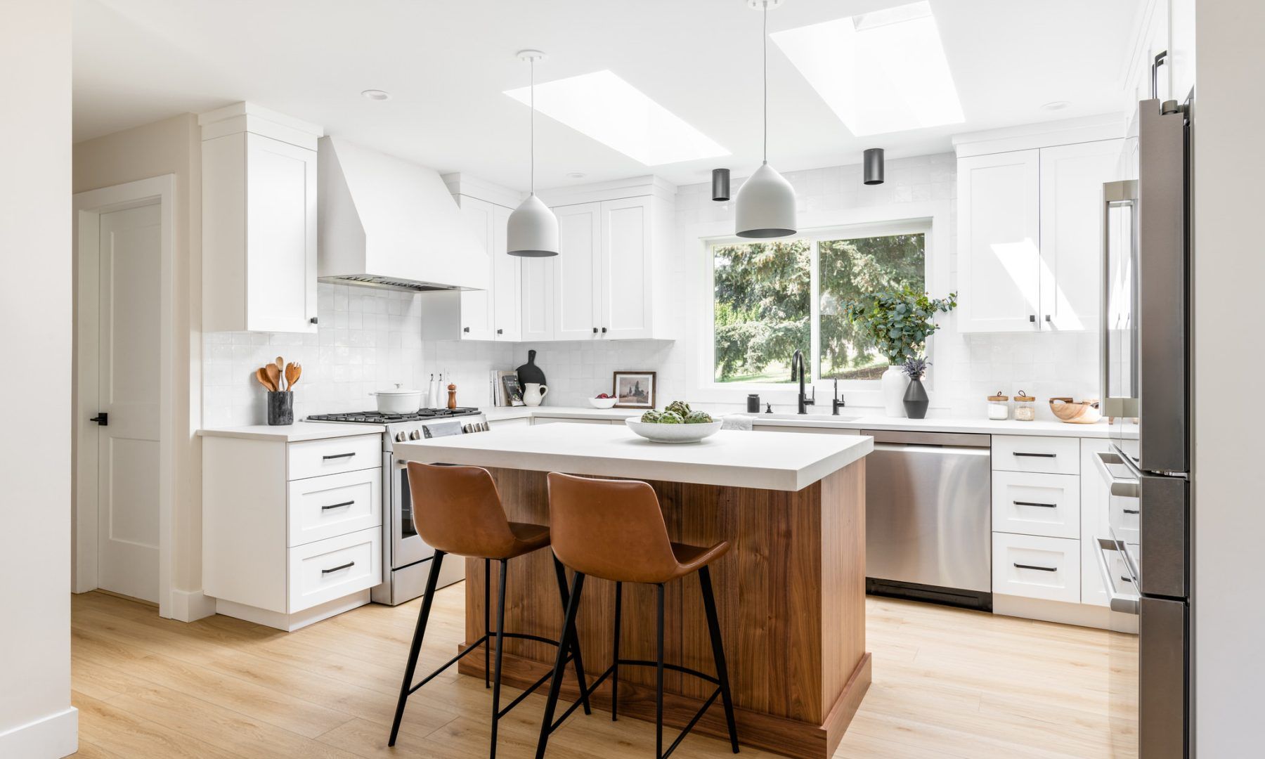 A kitchen with white cabinets , stainless steel appliances , and a wooden island.