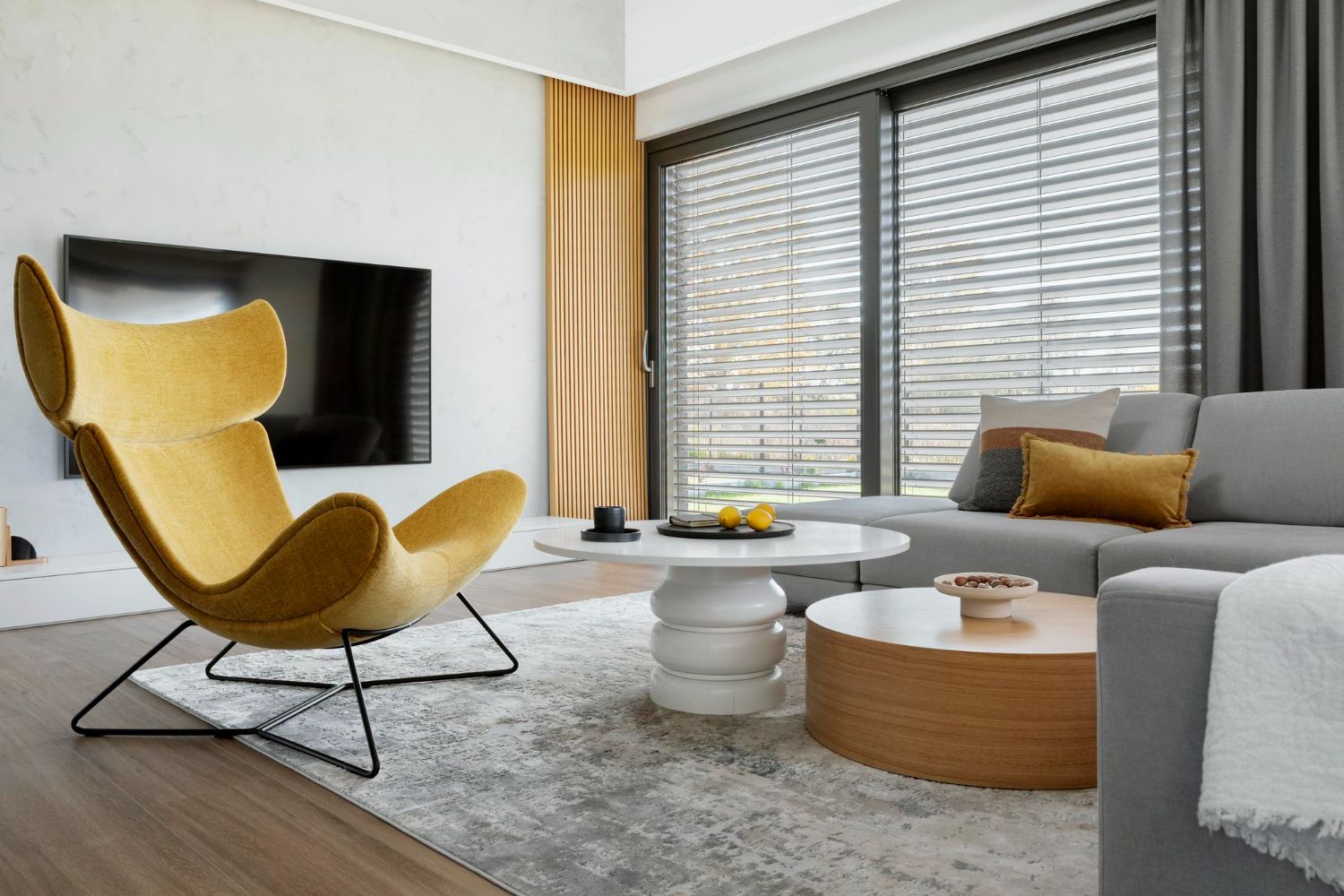 A living room with a yellow chair , couch , coffee table and television.