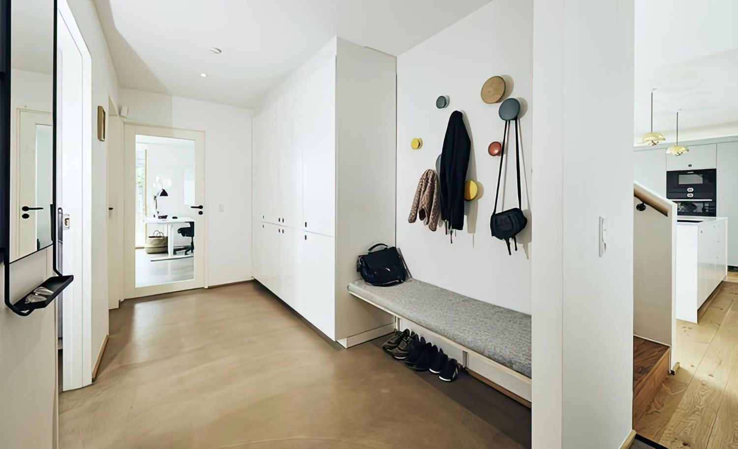 A hallway with a bench and hooks on the wall.