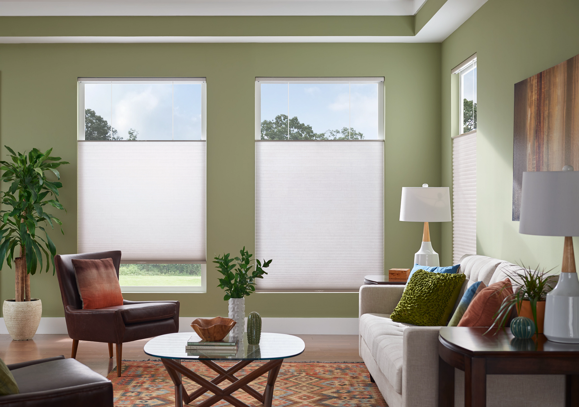 A living room with a couch , chair , coffee table and two windows.