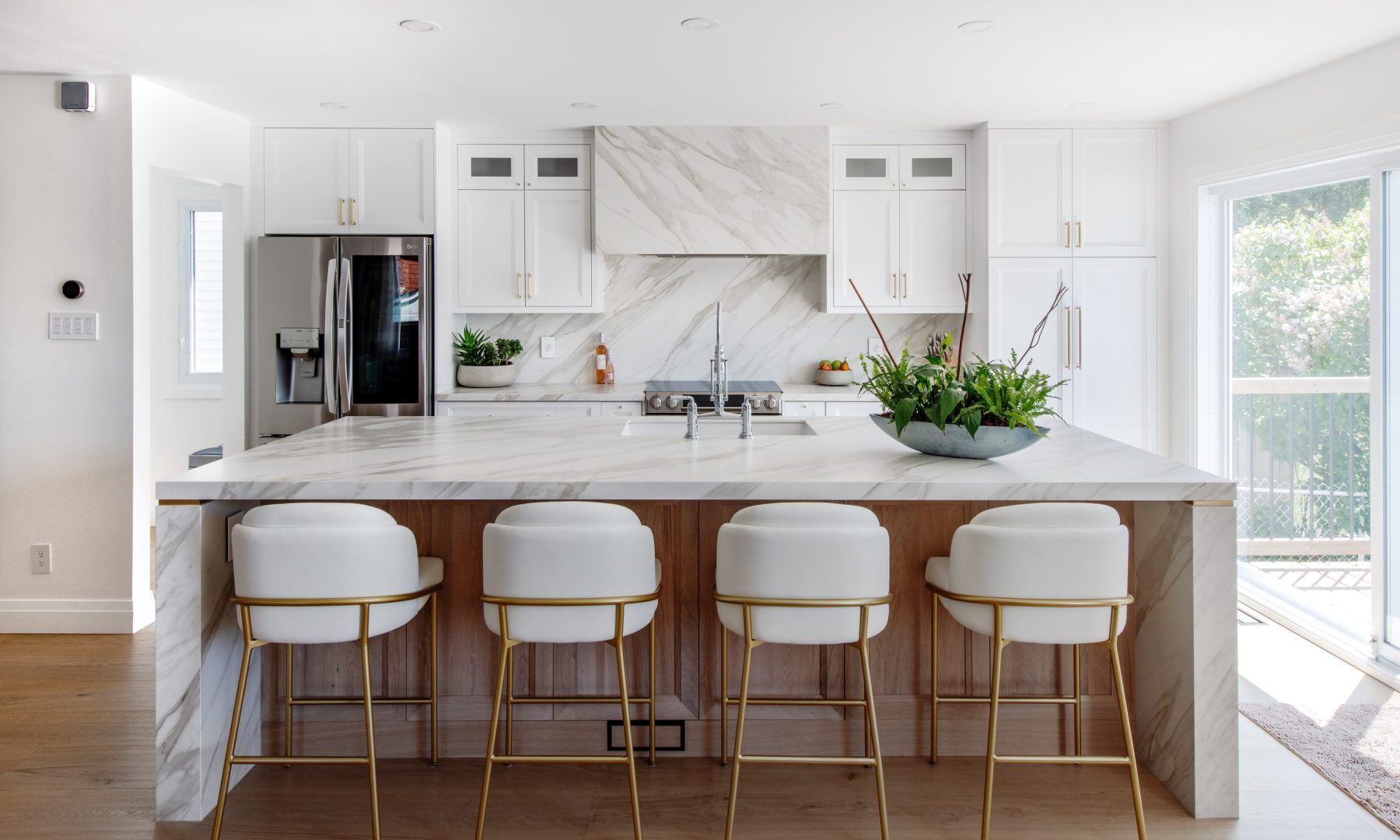 A kitchen with white cabinets and gold bar stools