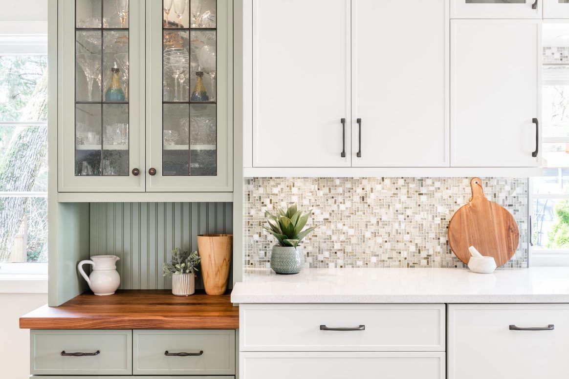 A kitchen with white cabinets and a wooden counter top.