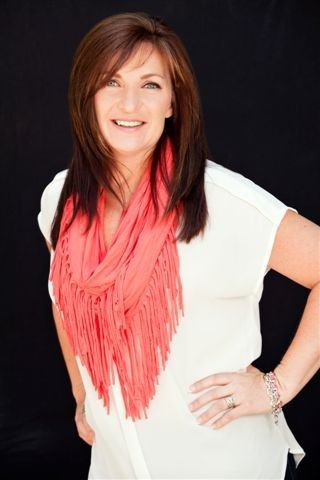 A woman wearing a white shirt and a red scarf is smiling.