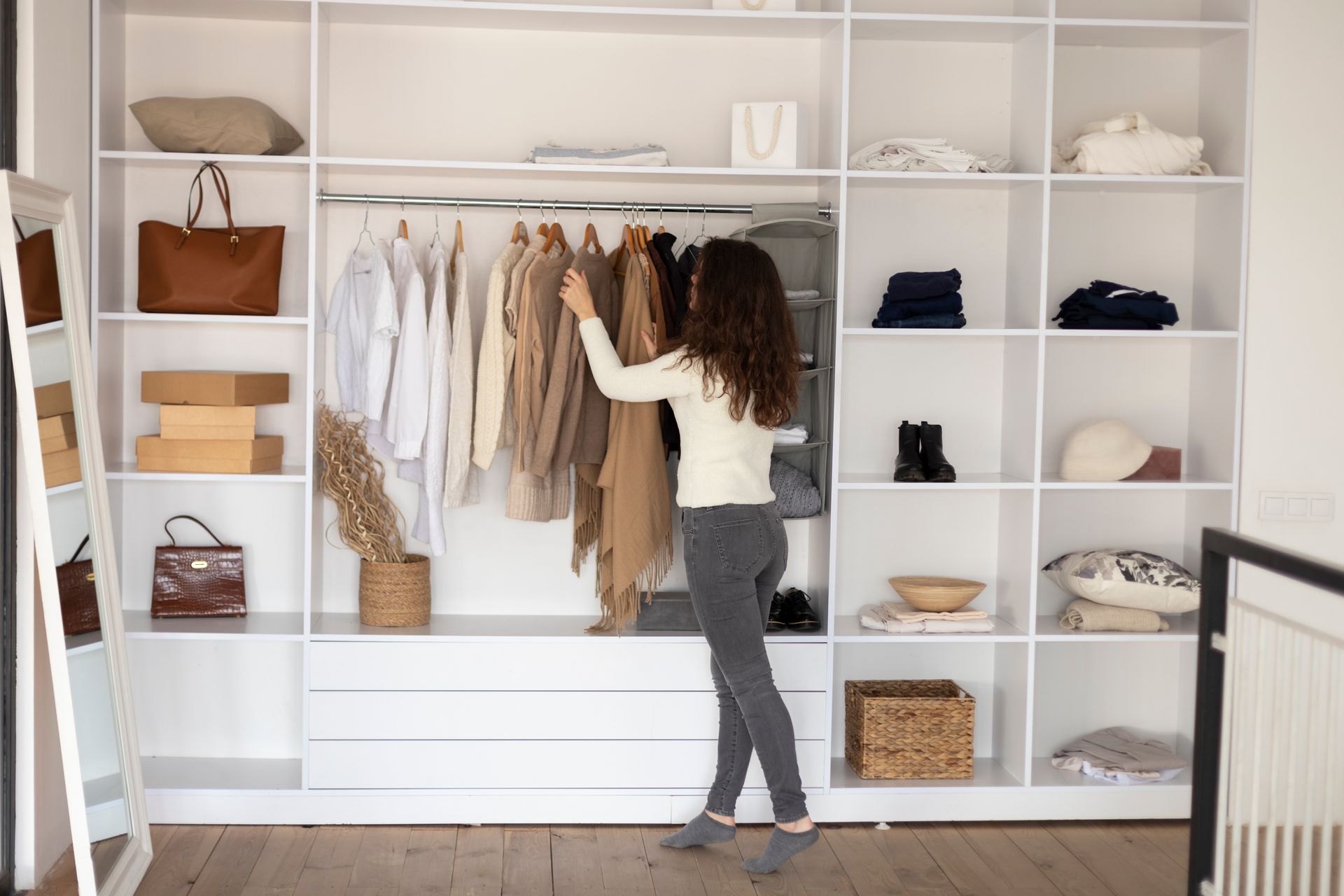 A woman is standing in a closet looking at clothes.