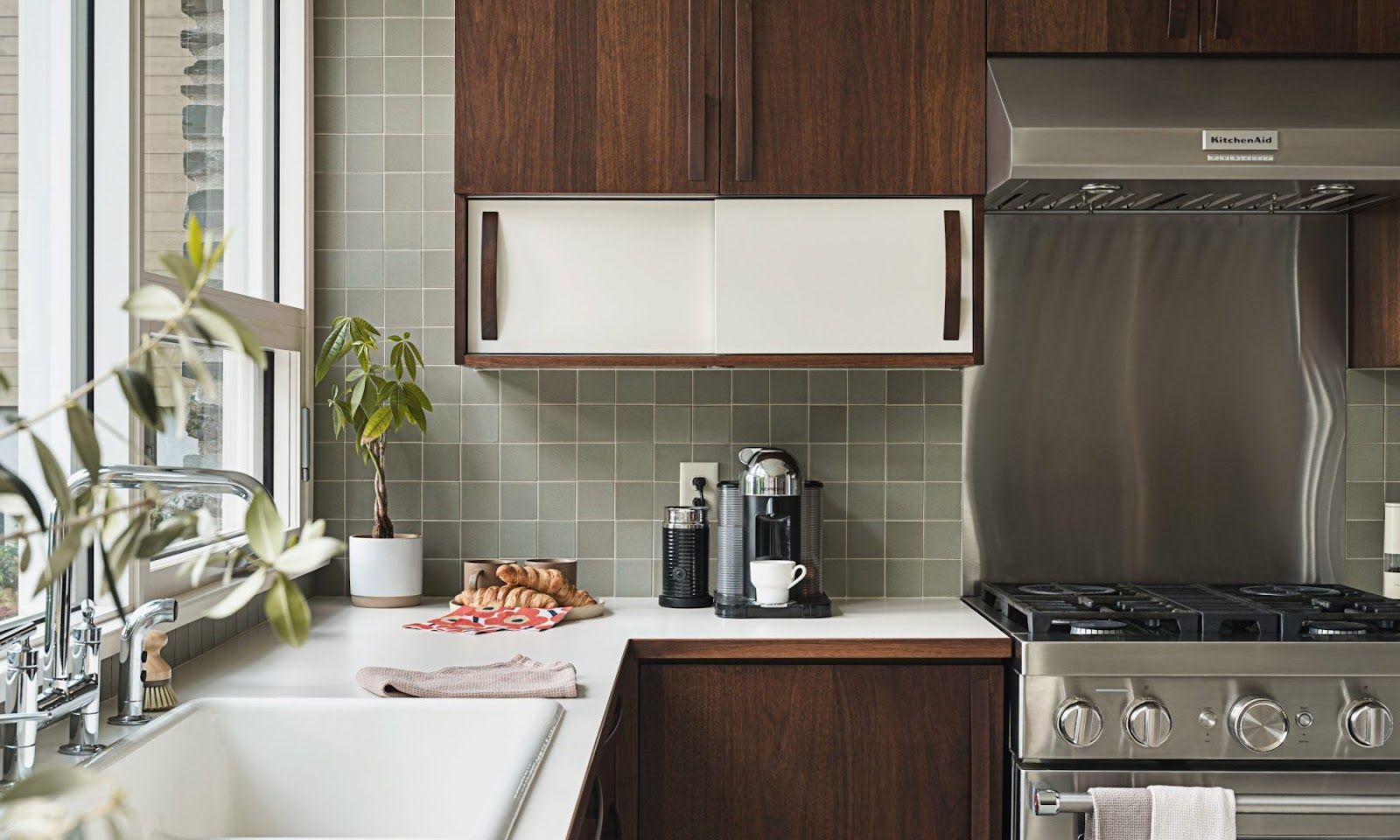 A kitchen with stainless steel appliances , wooden cabinets , a sink , and a stove.