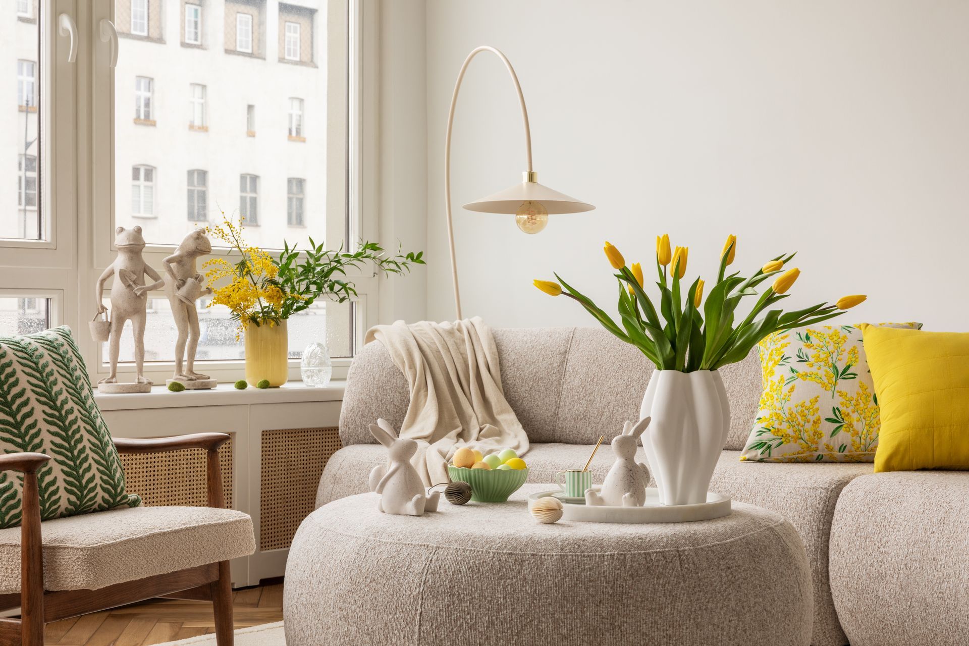 A living room with a couch , chair , coffee table and vase of flowers.