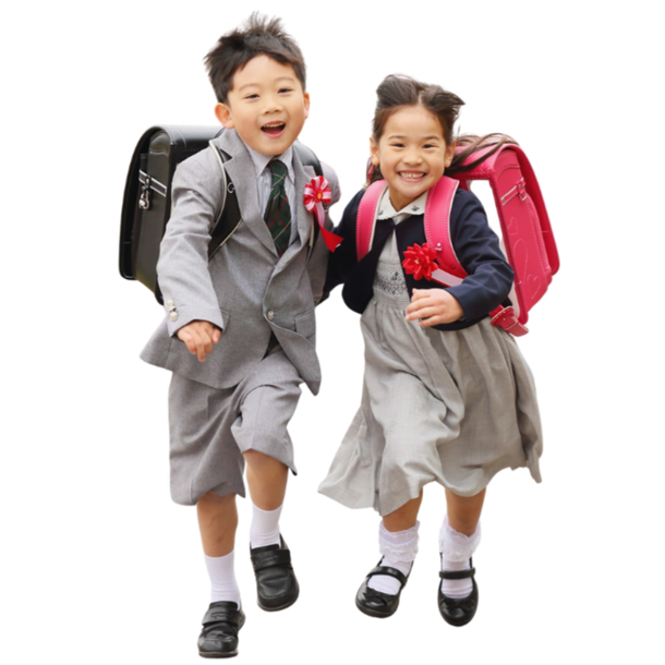 Two Asian children in school uniforms, happily running with backpacks.