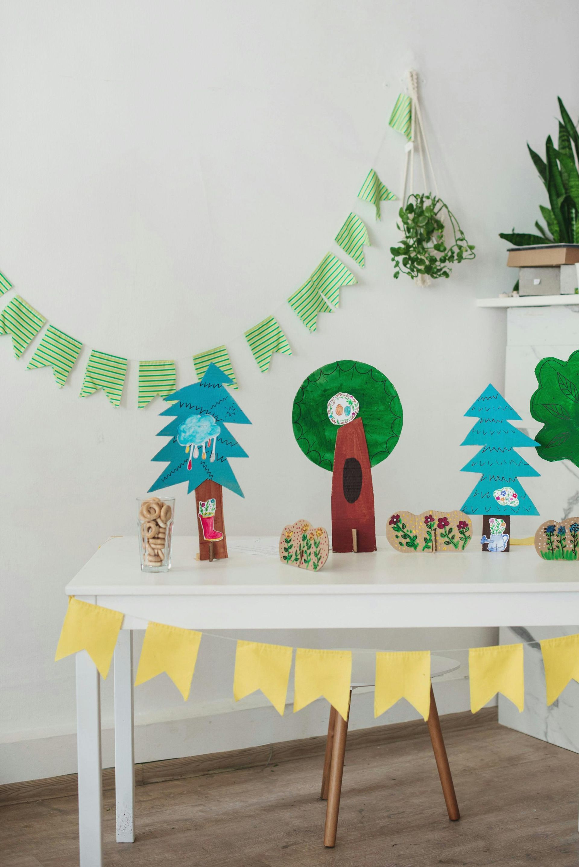 A table with woodland-themed decorations: trees, a bear, and a banner, all in green, blue, and brown.