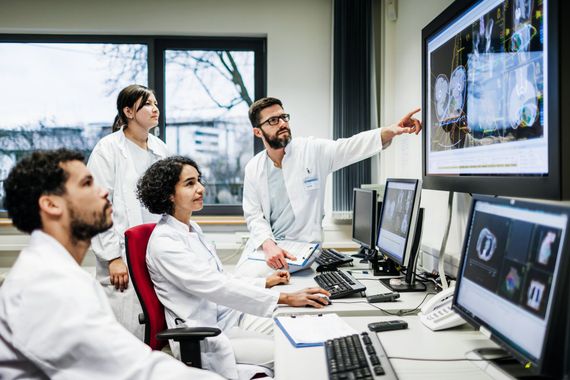 Un gruppo di medici sta guardando lo schermo di un computer.