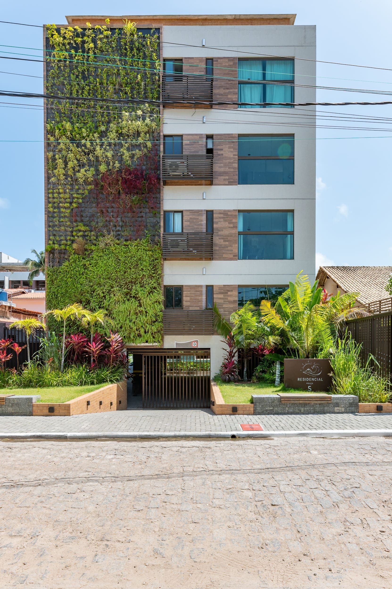 Um edifício alto com uma parede verde ao lado.