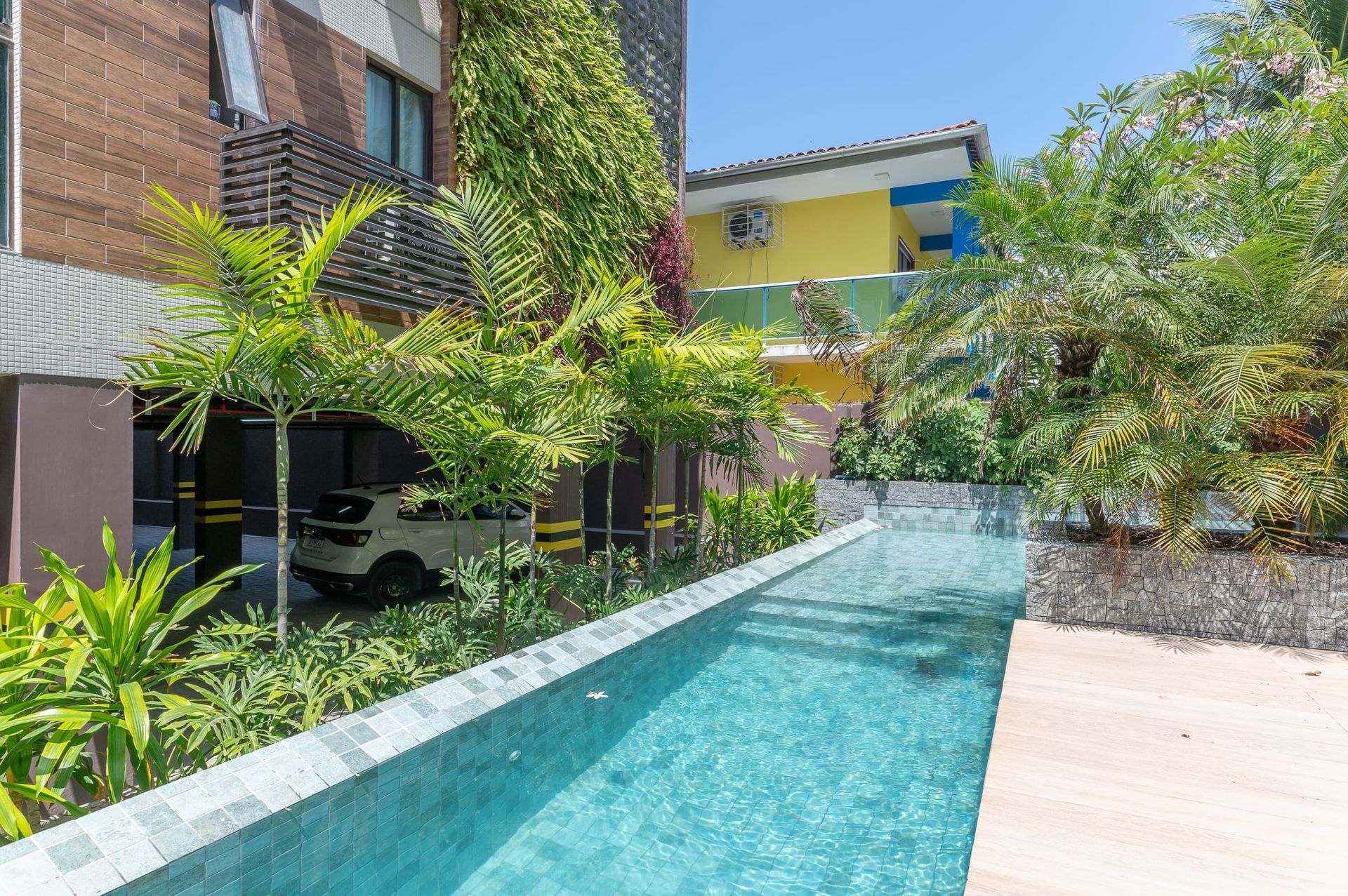 Uma grande piscina é cercada por árvores e um edifício.