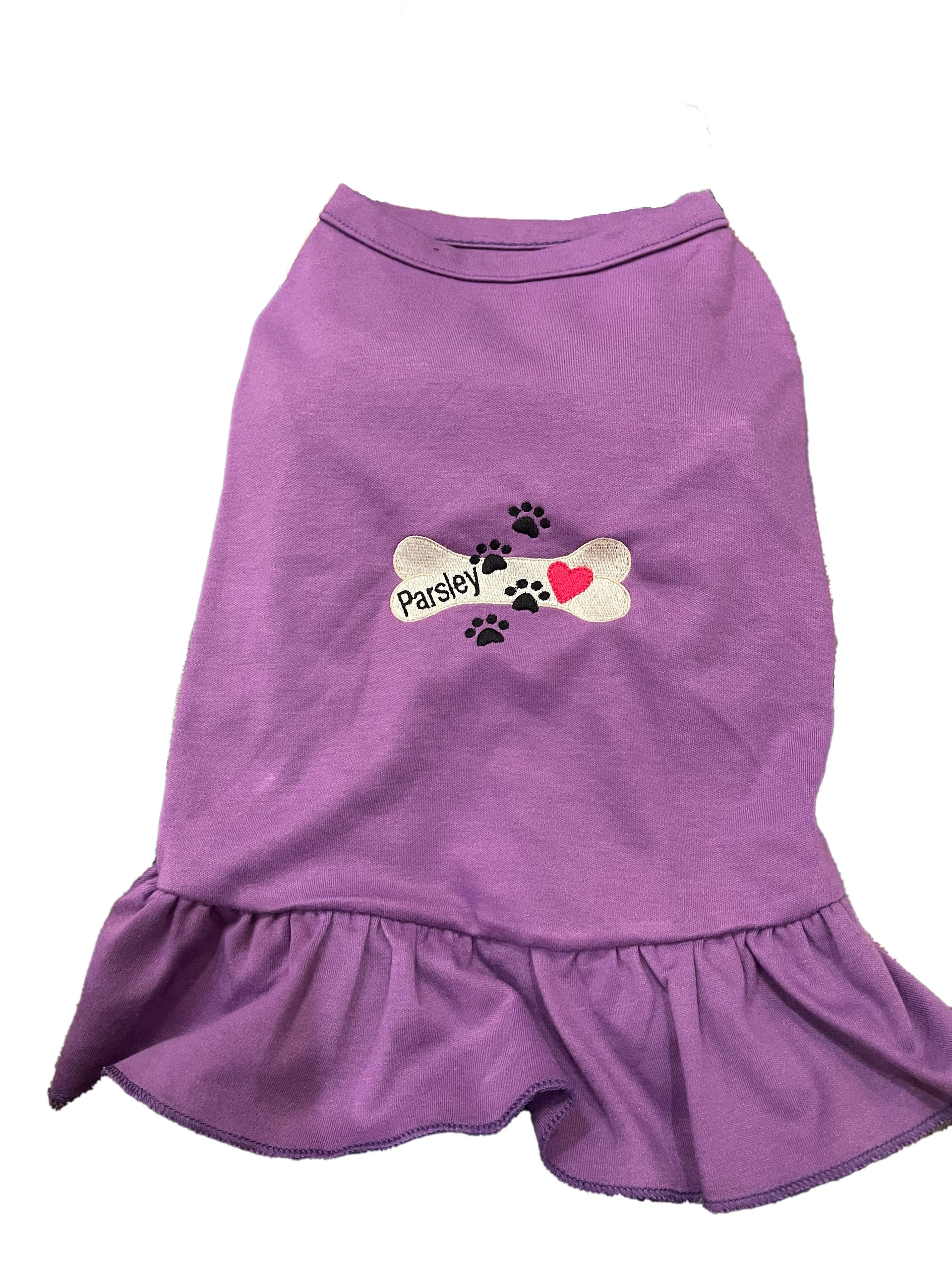 Pet dress with ruffle. Includes embroidered design with paw print, dog bone, and heart, plus name.
