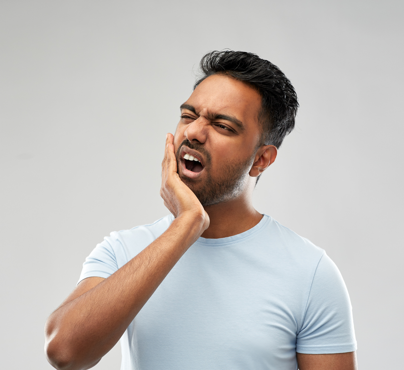 A man is holding his face in pain because he has a toothache.