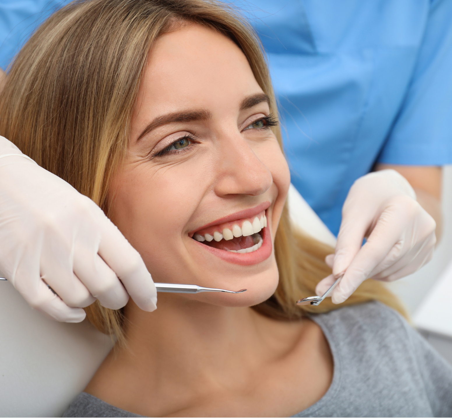 A woman is smiling while having her teeth examined by a dentist.