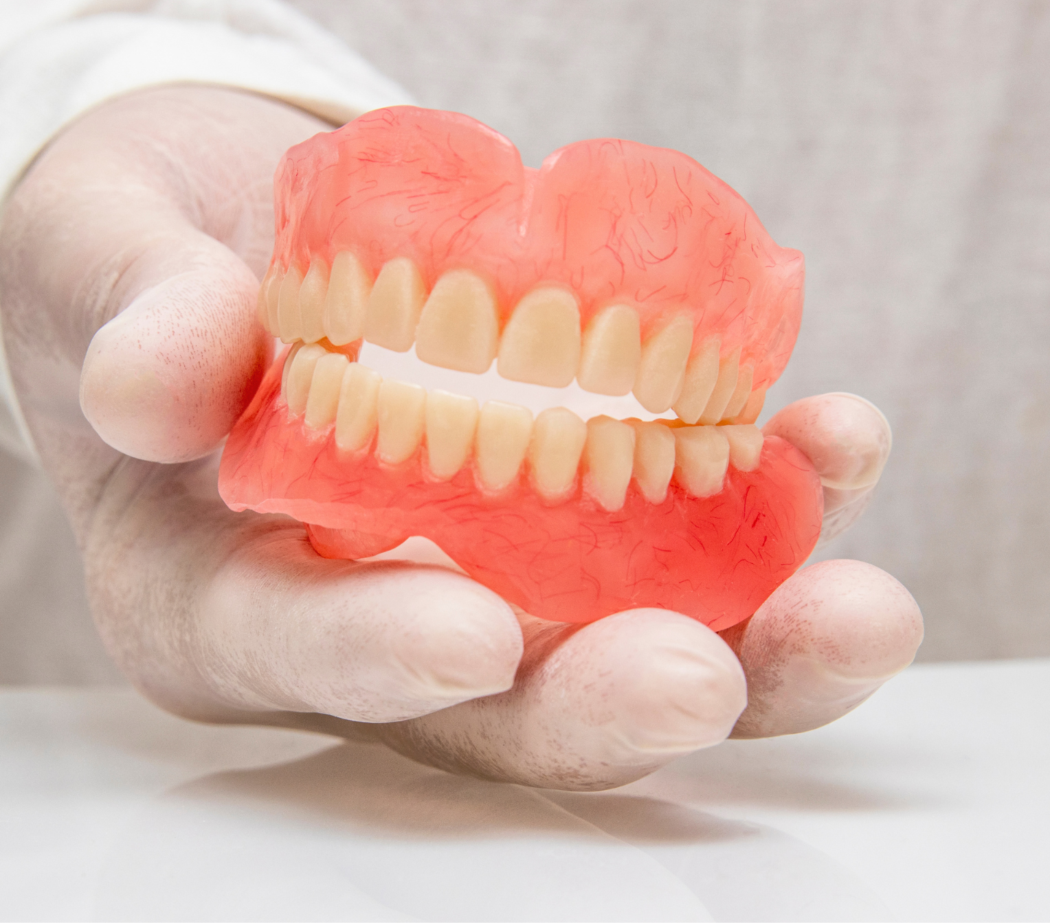 A person is holding a denture in their hand.