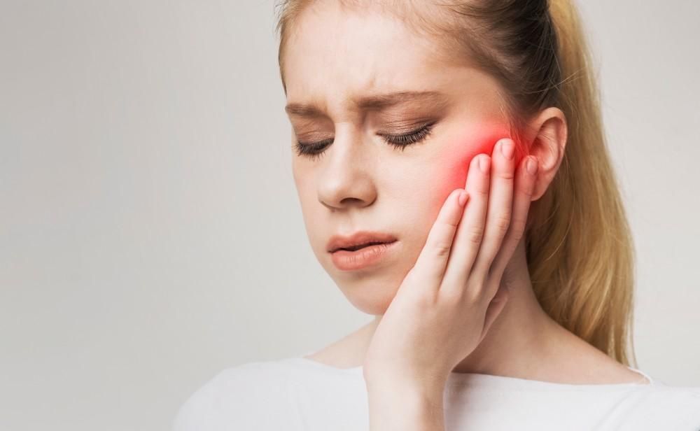 A woman is holding her face in pain because of a toothache.