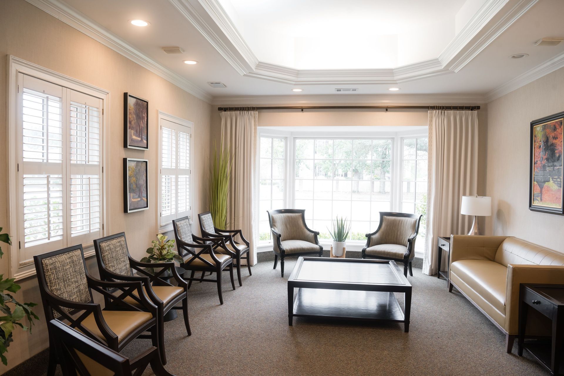 A waiting room with a couch , chairs , and a coffee table.