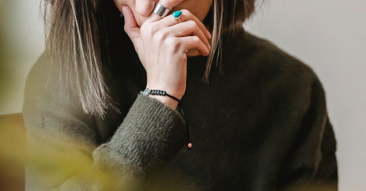 A woman in a green sweater is covering her mouth with her hand.