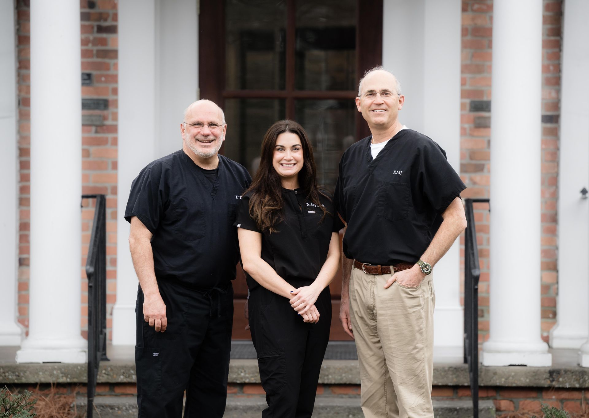 Three people are posing for a picture in front of a building.