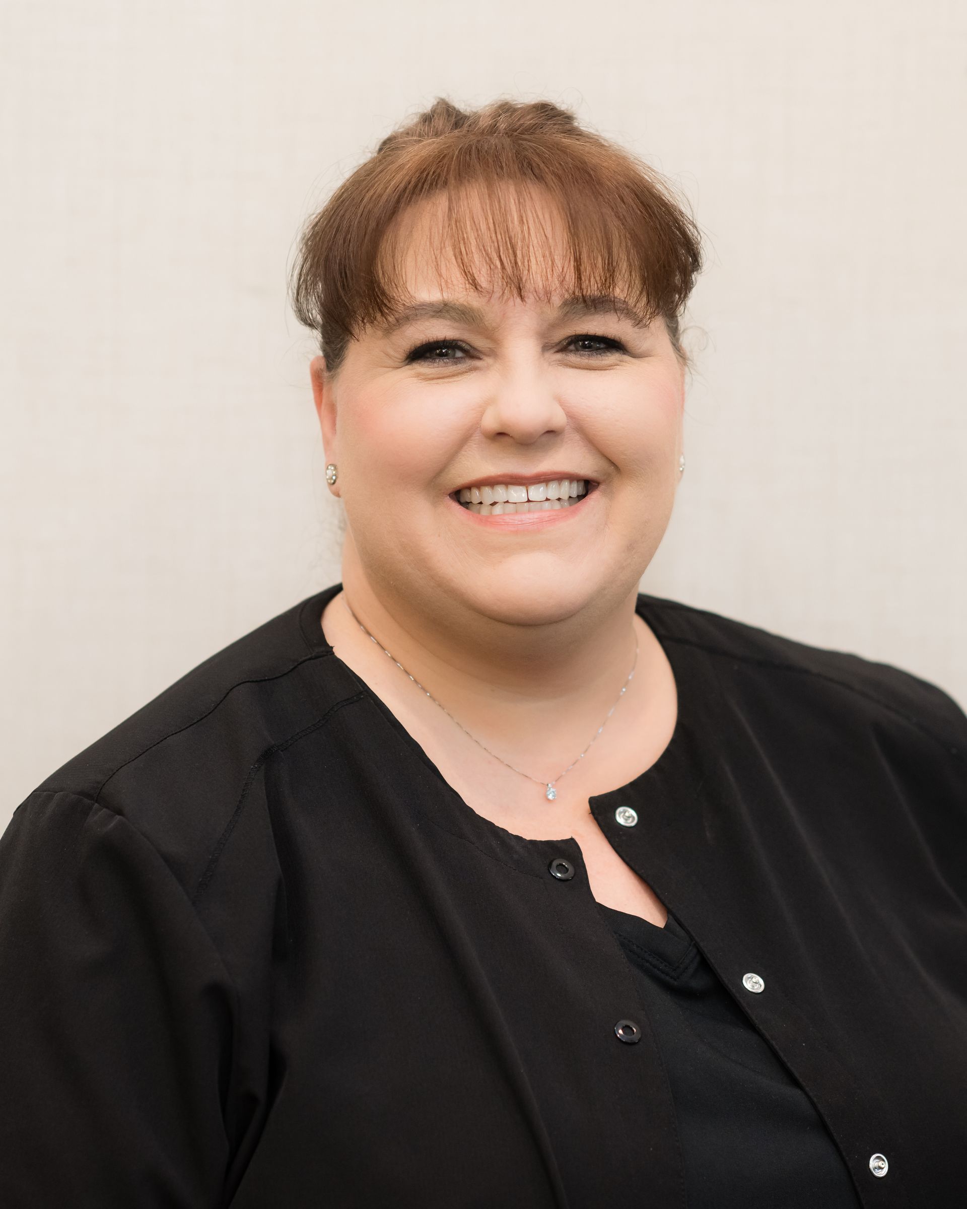 A woman in a black shirt is smiling for the camera.