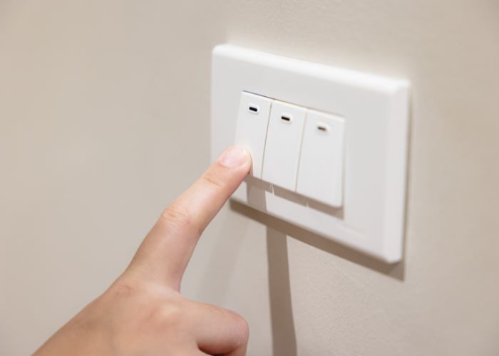 Image of finger pushing button to turn off light swtich