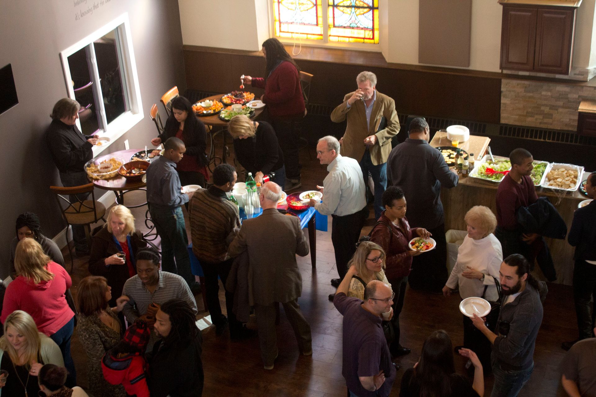 A large group of people are gathered in a room eating and drinking