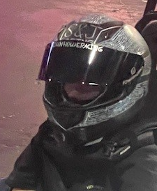 Motorcycle rider wearing a silver and black helmet with a tinted visor.