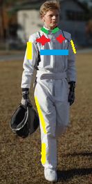 A person in a white racing suit holding a helmet, walking on a grassy field.