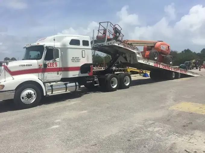 A semi truck with a flatbed trailer is parked in a parking lot.