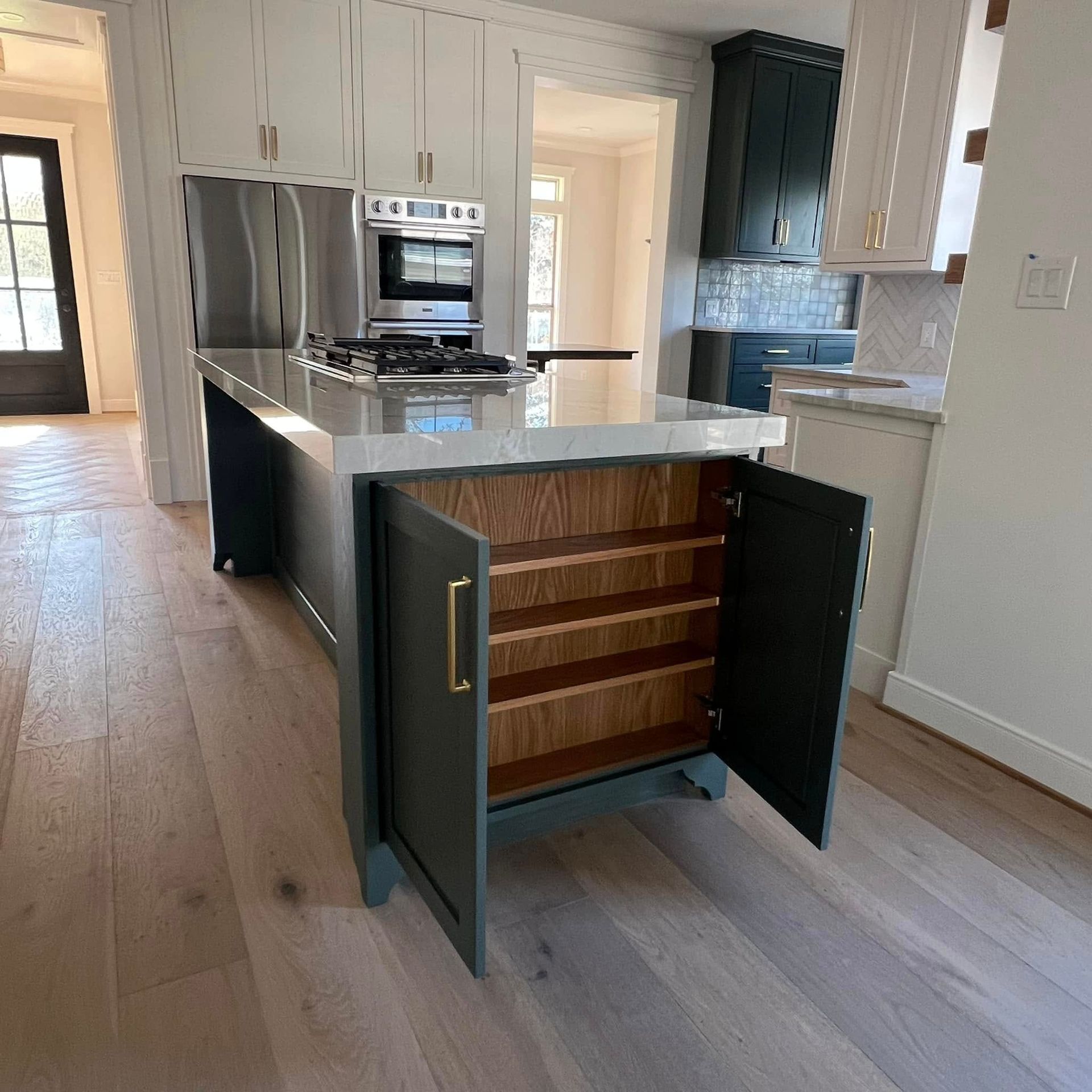 A modern kitchen features light grey cabinets, white marble-look countertops, a white subway tile backsplash, and a sink.