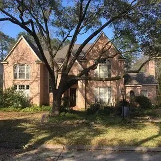 A large brick house with a tree in front of it.